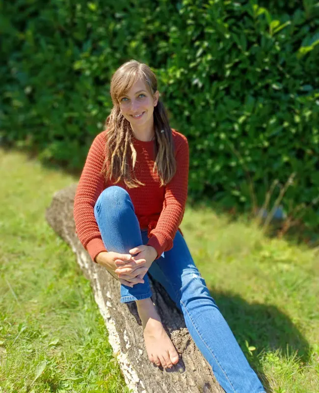 Marina Rauchfuss sitzend auf einem Baumstamm
